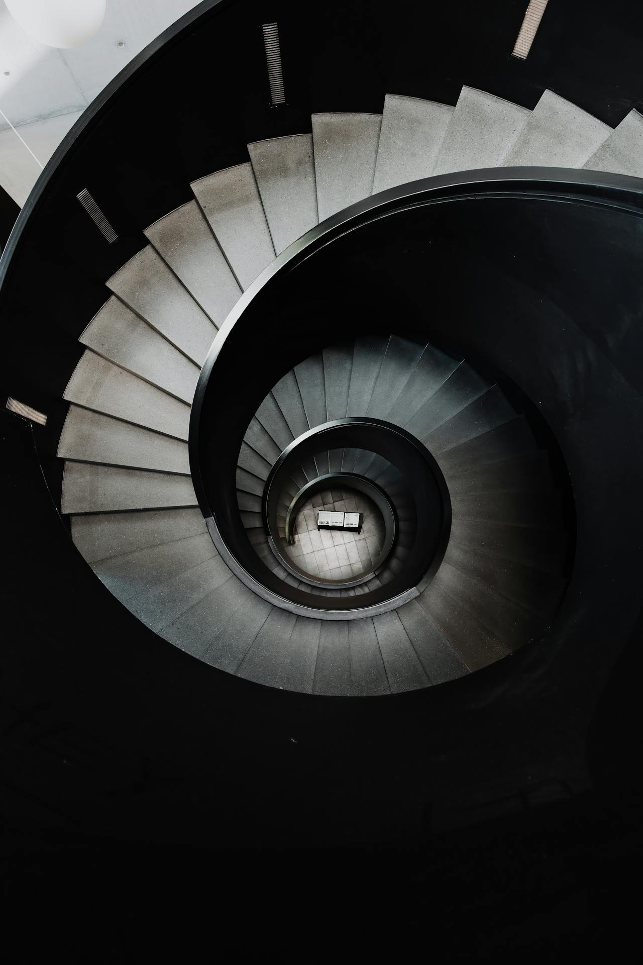 Spiral staircase viewed from above, symbolising the structured, developmental journey of psychotherapy training over time.